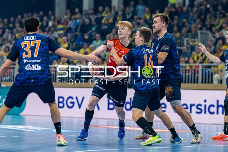 Ein Spieler von Rhein Neckar Löwen versucht, den Ball zu passen oder zu werfen, während er von der gegnerischen Abwehr bedrängt wird.