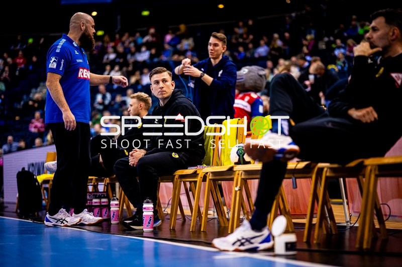 Teammitglieder auf der Bank, Trainer spricht mit Spielern