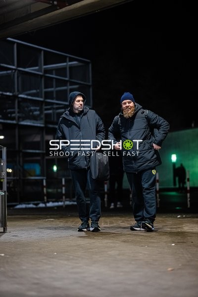 Trainer unterhalten sich außerhalb einer Sporthalle.