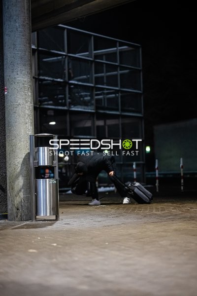 Eine Person zieht einen Koffer auf einem Gehweg.