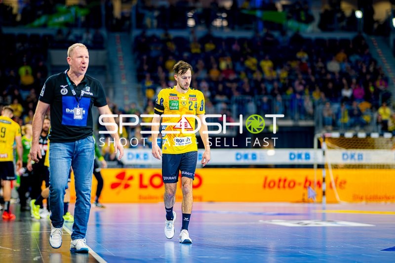 Der Spieler und der Trainer gehen am Spielfeldrand entlang.