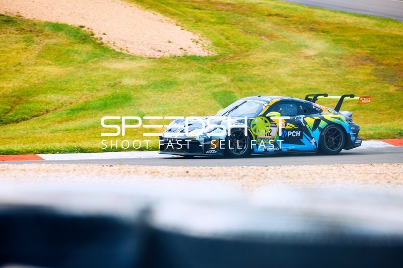 Ein Rennwagen fährt eine Kurve auf der Strecke des 24h Nürburgrings.