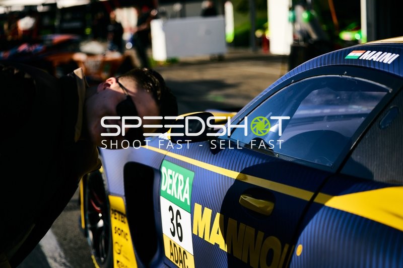 Ein Mann posiert neben einem Rennwagen.