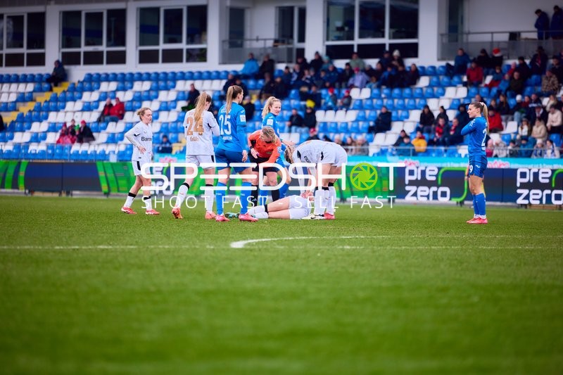 Eine verletzte Spielerin von Bayer Leverkusen wird auf dem Feld betreut.