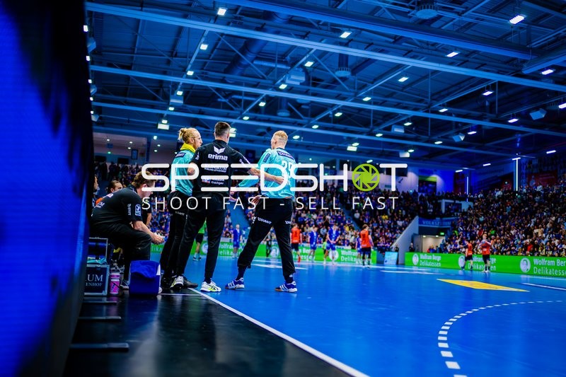 Ein Spieler der Rhein-Neckar Löwen im türkisfarbenen Torwarttrikot steht am Spielfeldrand mit einem Trainer.