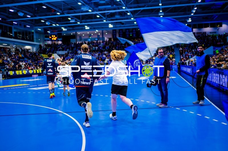 Fans und Spieler des VfL Gummersbach laufen mit einer großen blauen Flagge in die Halle ein.