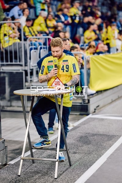 Ein Fan oder Teammitglied steht am Spielfeldrand an einem Stehtisch.