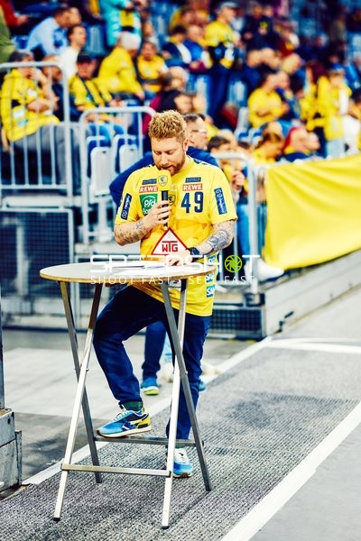 Ein Fan oder Teammitglied steht am Spielfeldrand an einem Stehtisch.