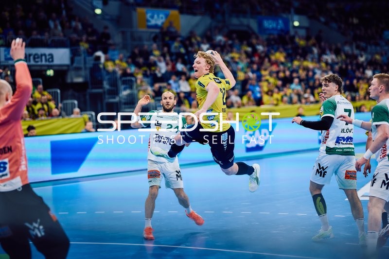 Ein Spieler von Rhein-Neckar Löwen springt, um einen Wurf zu machen, während ein Spieler von Frisch Auf Göppingen verteidigt.