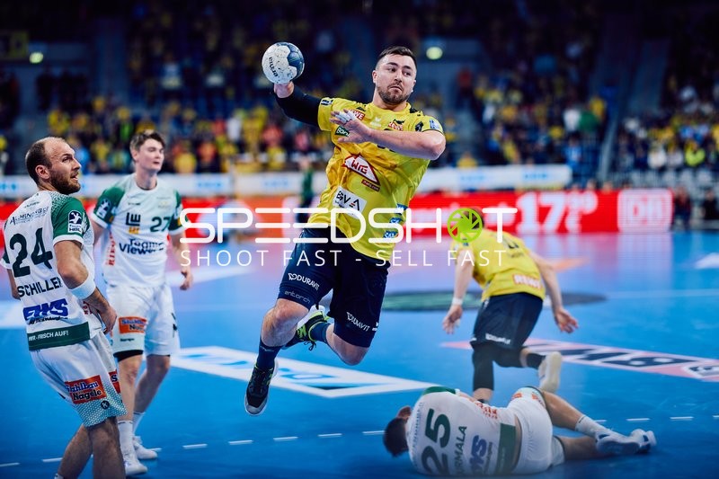 Ein Spieler der Rhein Neckar Löwen im gelben Trikot springt mit einem Wurfversuch.