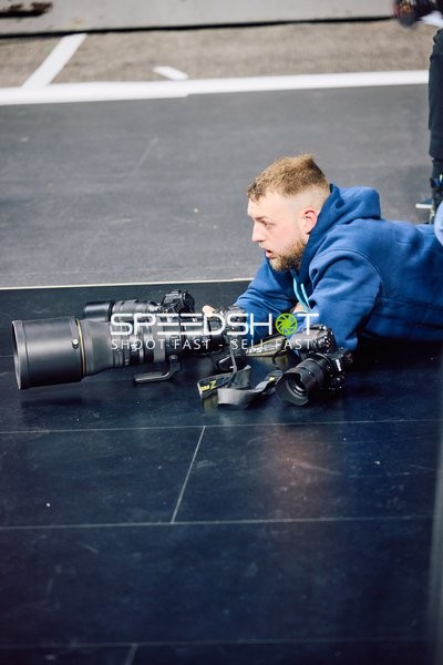 Ein Fotograf liegt auf dem Boden und bereitet ein Foto vor.