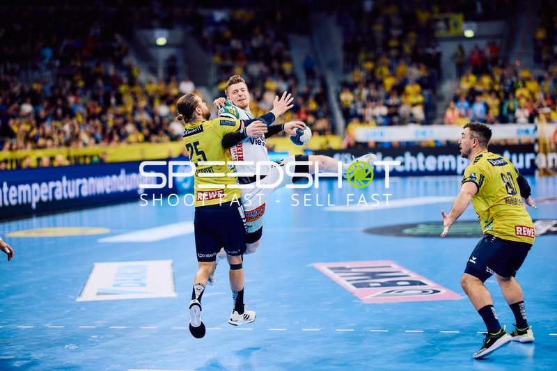 Ein Spieler von Frisch Auf Göppingen springt für einen Wurf, während zwei Spieler von Rhein Neckar Löwen verteidigen.