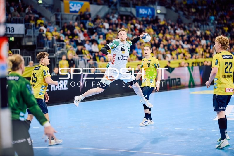 Ein Spieler von Frisch Auf Göppingen springt zum Wurf, während mehrere Spieler der Rhein Neckar Löwen verteidigen.