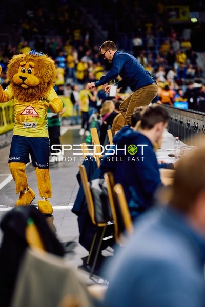 Das Maskottchen der Rhein-Neckar Löwen interagiert mit Personen am Spielfeldrand.