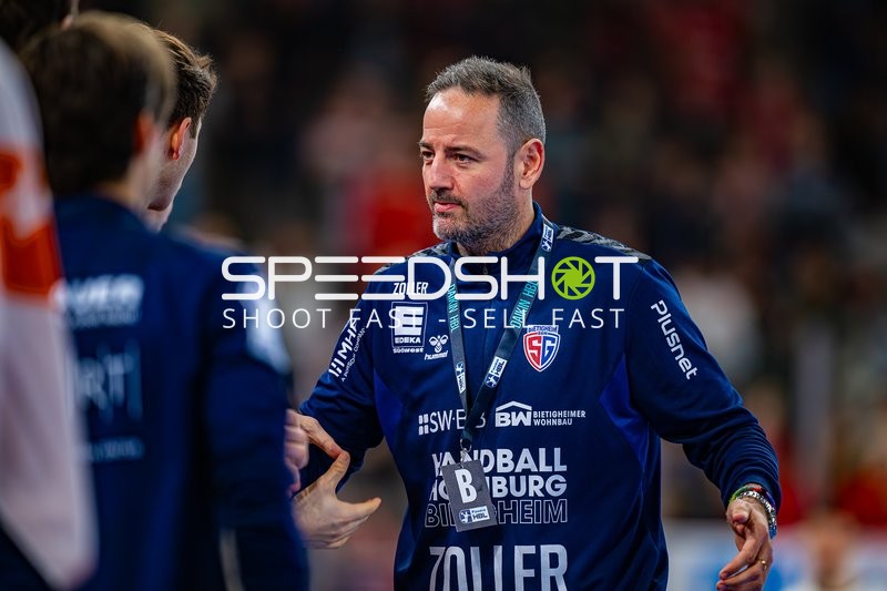 Der Trainer von SG BBM Bietigheim in Diskussion mit Spielern am Spielfeldrand.