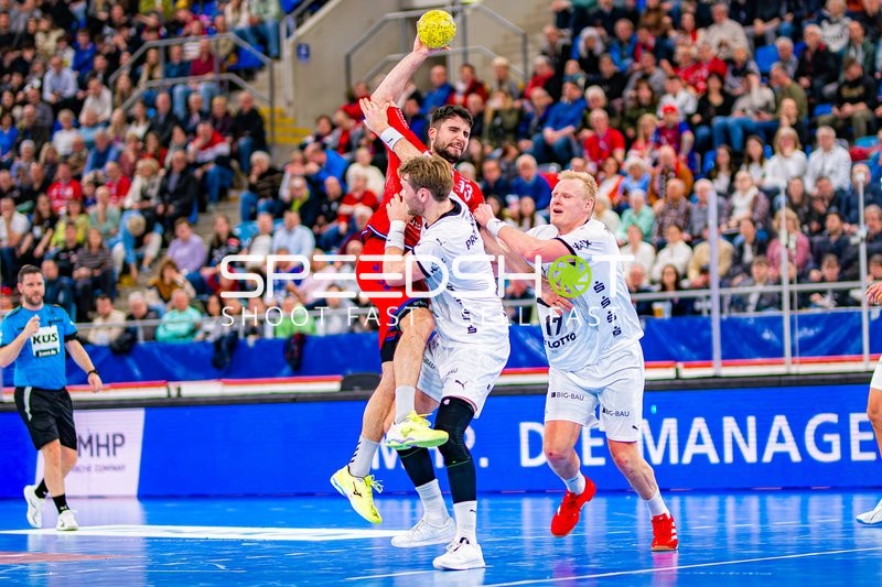 Ein Spieler von SG BBM Bietigheim springt, um ein Tor zu werfen, während er von einem Verteidiger von THW Kiel blockiert wird.