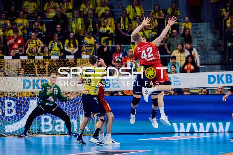 Ein Spieler des TSV Hannover Burgdorf springt zum Wurf, während Spieler der Rhein-Neckar Löwen verteidigen.