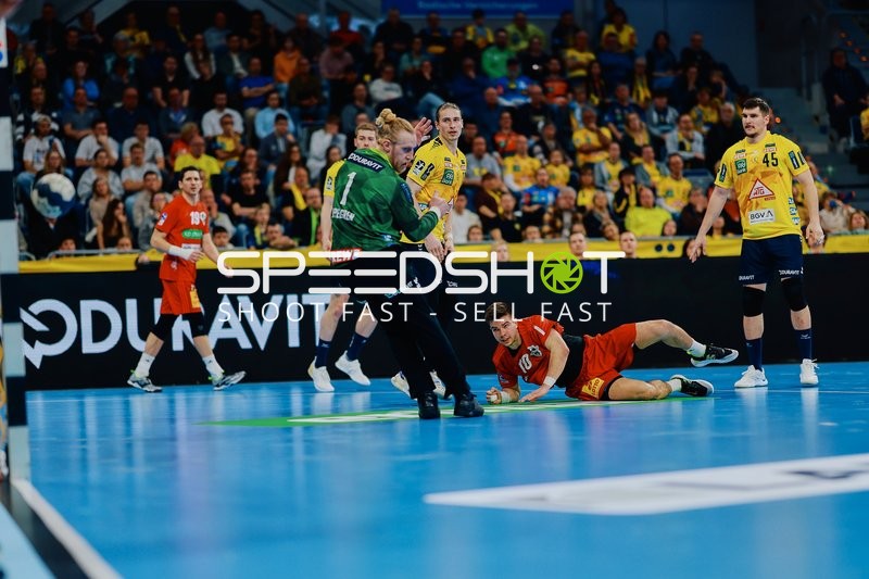 Ein Spieler der Rhein Neckar Löwen verteidigt gegen einen Spieler der TSV Hannover Burgdorf, der am Boden liegt.