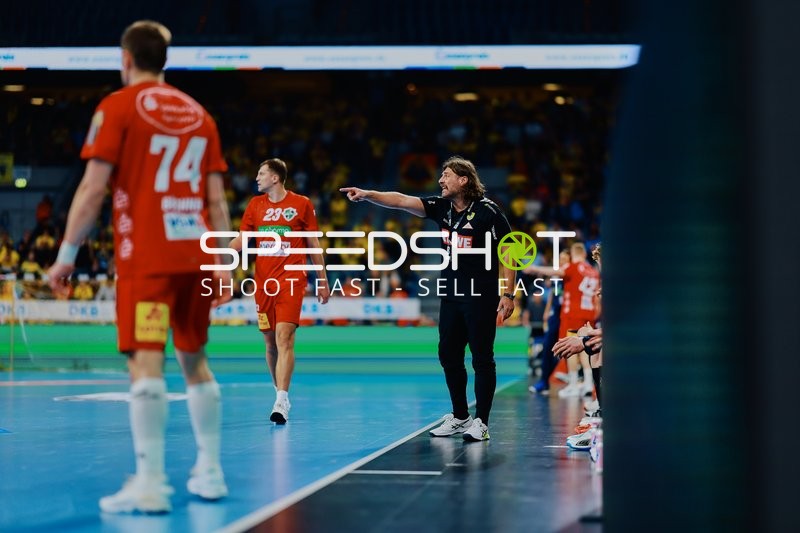 Ein Spieler von TSV Hannover Burgdorf und ein Trainer auf dem Spielfeld