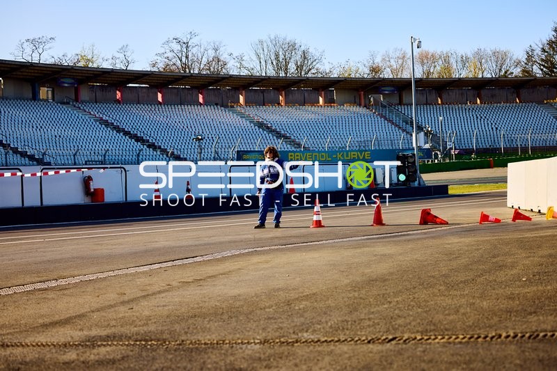 Person in Blau auf der Rennstrecke neben Verkehrskegeln