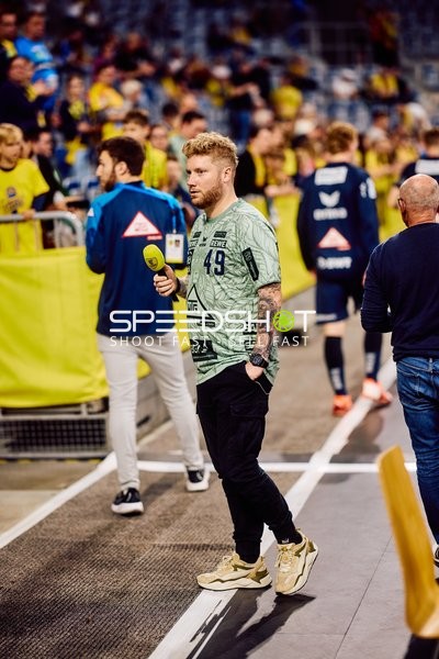 Moderator mit Mikrofon am Spielfeldrand