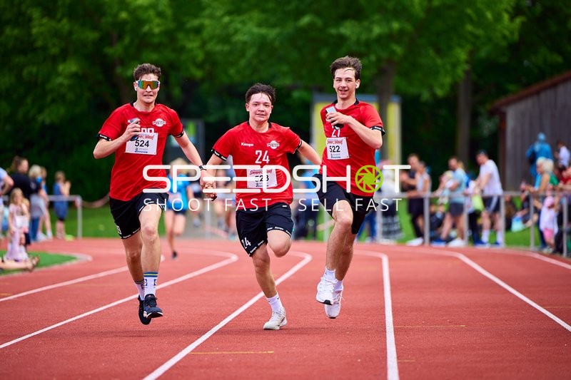 TVE Sommerlauf Edingen 2025: Läufer mit den Startnummern 522, 523 und 524 laufen Hand in Hand auf der Laufbahn im TVE Sportzentrum.