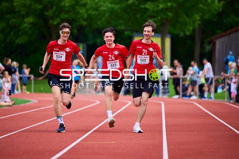 TVE Sommerlauf Edingen 2025: Läufer mit Startnummern 522, 523 und 524 laufen Hand in Hand auf der Laufbahn im TVE Sportzentrum.