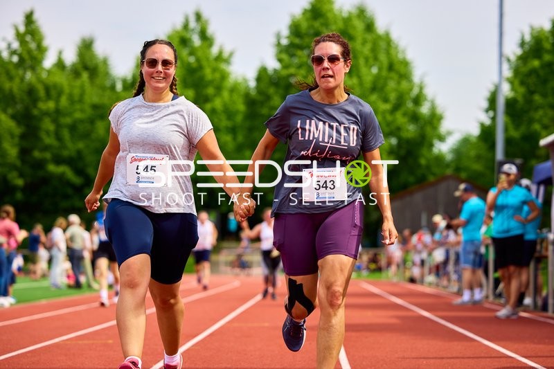 TVE Sommerlauf Edingen 2025: Läuferinnen laufen Hand in Hand ins Ziel am TVE Sportzentrum.