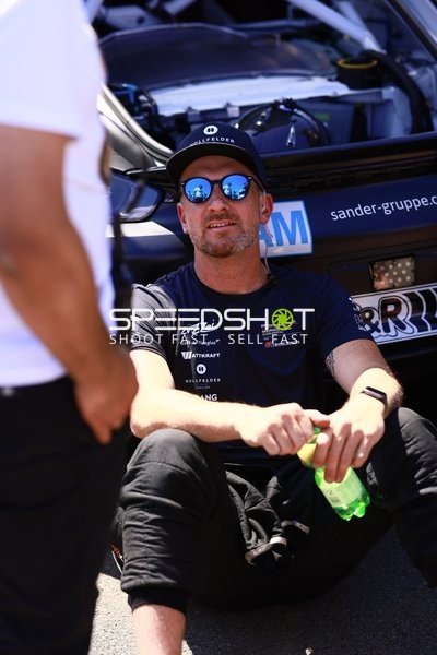 Person neben Rennfahrzeug in Boxengasse