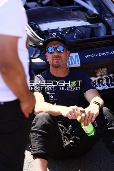 Person neben Rennfahrzeug in der Boxengasse