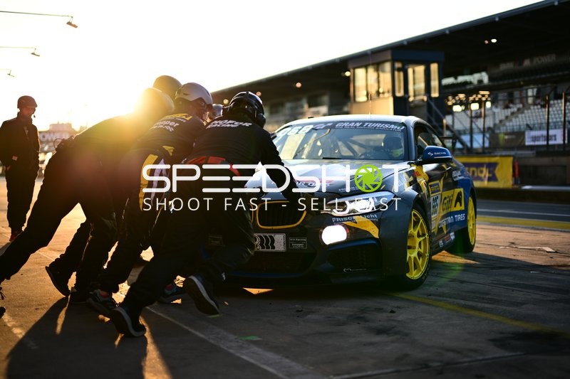 Mechaniker schieben Rennfahrzeug in Boxengasse