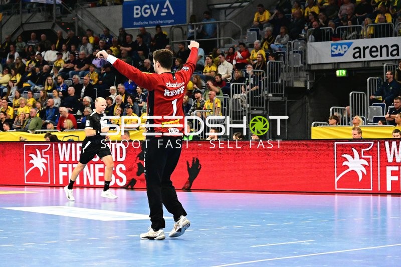 Handballspieler mit erhobenen Armen vor Schiedsrichter