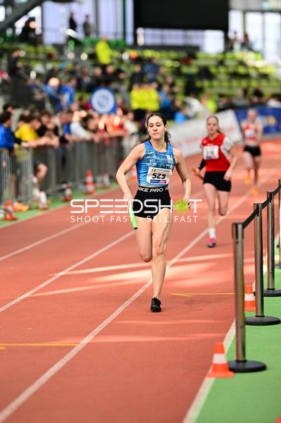 Athletin mit Staffelstab auf Bahn