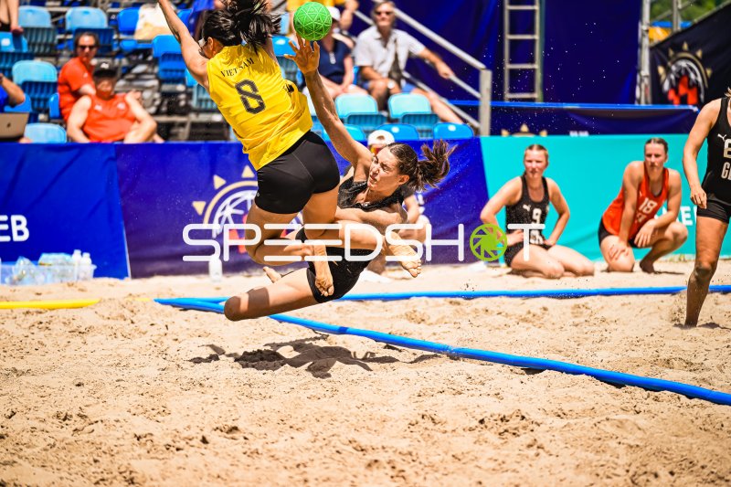 Vietnam-Spielerin (#8) im Wurf gegen deutsche Torfrau beim Beachhandball