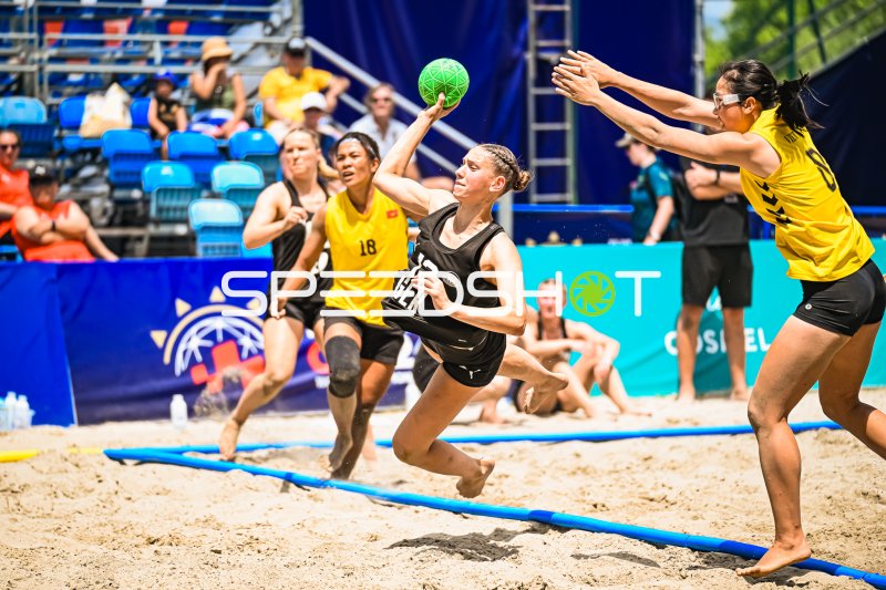 Deutsche Beachhandball-Spielerin (#12; GER) beim Wurfversuch gegen Gegenspielerin