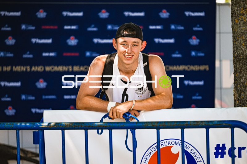 Lars Zelser (#6; Deutschland Beachhandball) lächelt am Absperrband in Zagreb