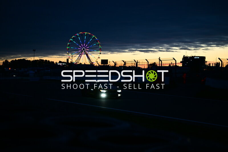Rennfahrzeug #106 bei Sonnenuntergang mit leuchtendem Riesenrad am Nürburgring