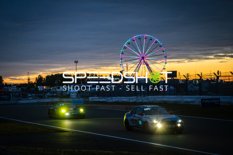 Zwei Rennwagen bei Sonnenuntergang mit Riesenrad am Nürburgring
