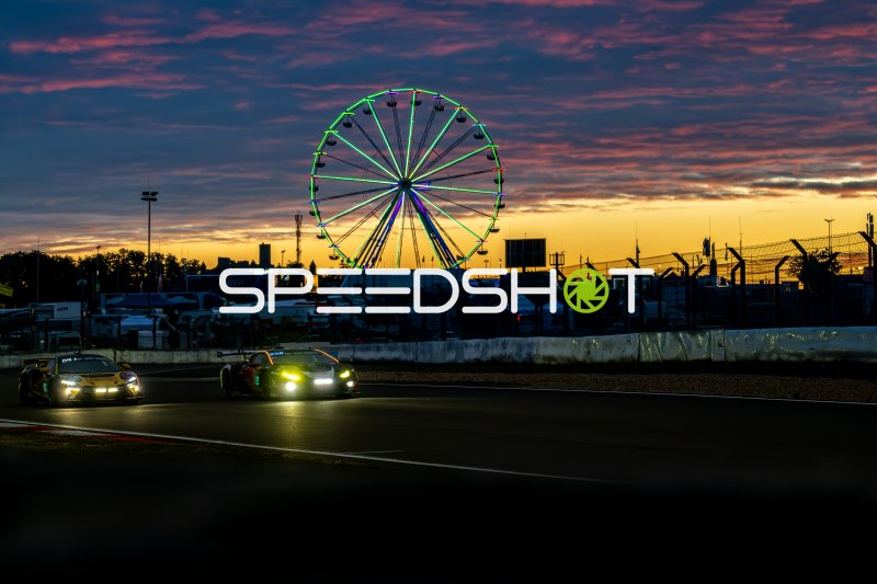 Zwei GT3-Fahrzeuge bei Sonnenuntergang am Nürburgring mit Riesenrad