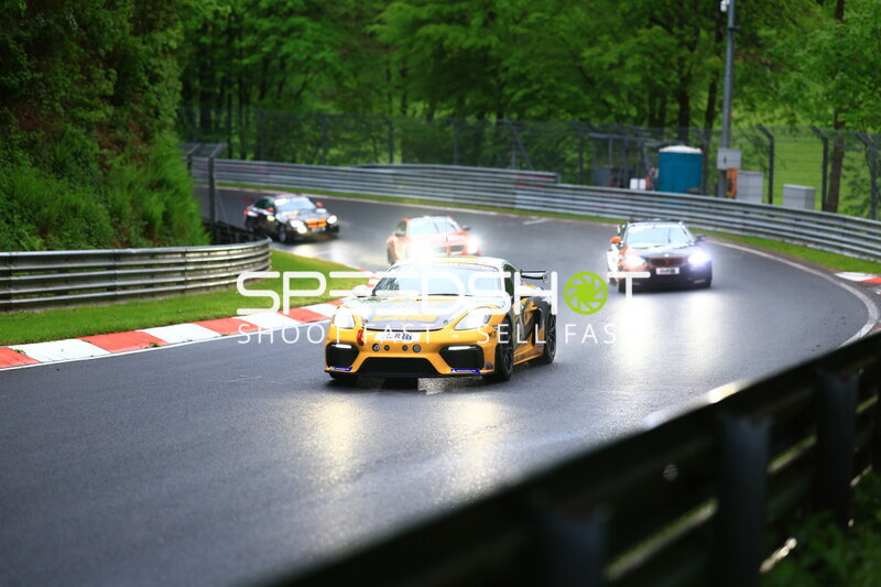 Gelber Porsche 718 Cayman GT4 auf nasser Nordschleife