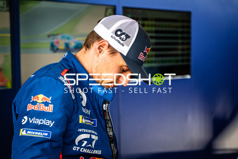 Fahrer im blauen Racing-Overall mit Red Bull und Viaplay im Fahrerlager