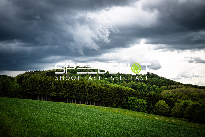 Dramatische Eifel-Landschaft mit dunklen Wolken über grünen Hügeln