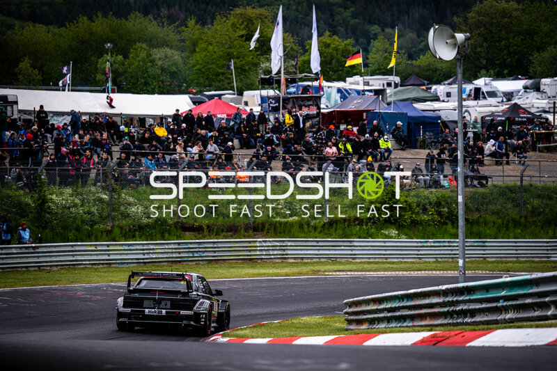 Schwarzes Rennfahrzeug in der Kurve am Nürburgring vor vollen Zuschauerrängen