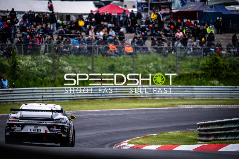 Porsche GT4 in der Kurve am Nürburgring mit Zuschauertribüne im Hintergrund