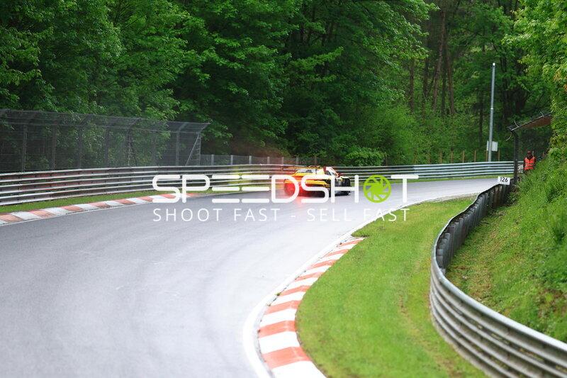Gelb-schwarzes GT3-Fahrzeug in Kurve auf nasser Nordschleife