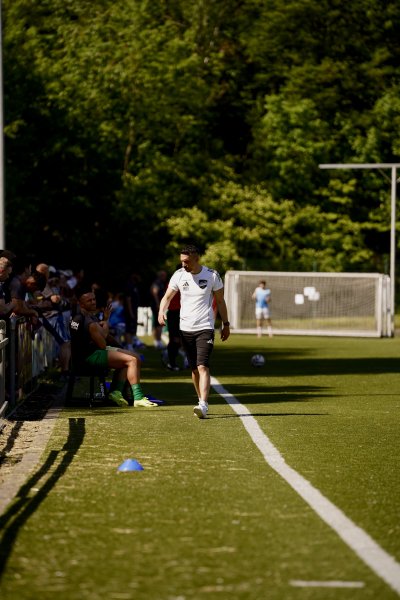 Trainer/Offizieller läuft am Spielfeldrand entlang