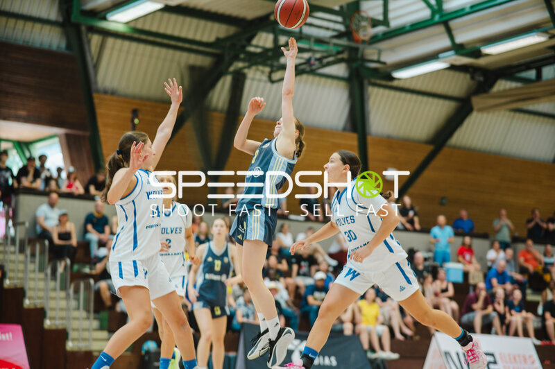 Basketballspielerin im Sprungwurf gegen Wolves-Defensive