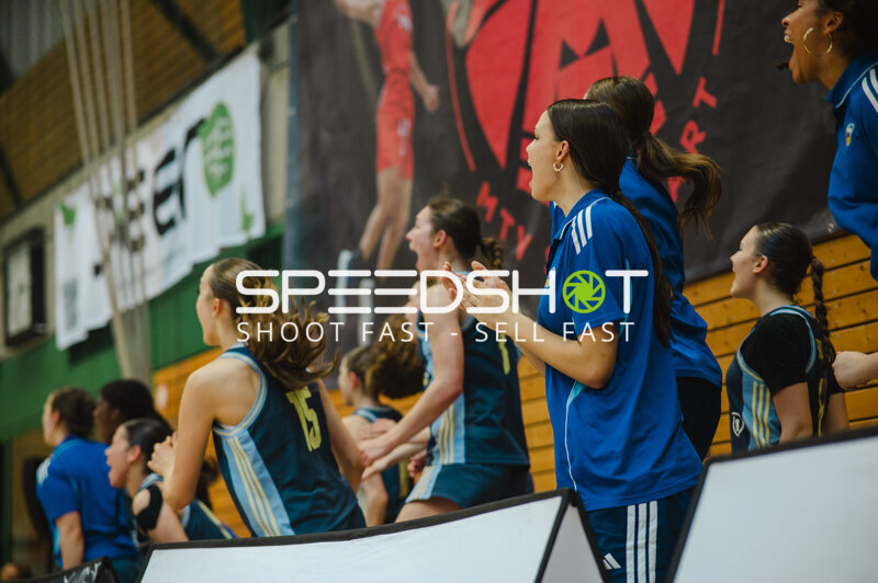 Basketballteam in blauem Trikot auf der Bank während Spielunterbrechung