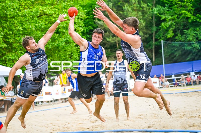 Spieler #34 im Sprungwurf gegen zwei Abwehrspieler beim Beachhandball