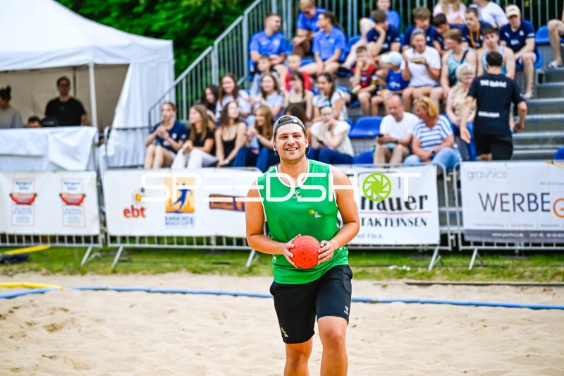 Spieler im grünen Trikot mit Ball beim Beach-Handball-Turnier